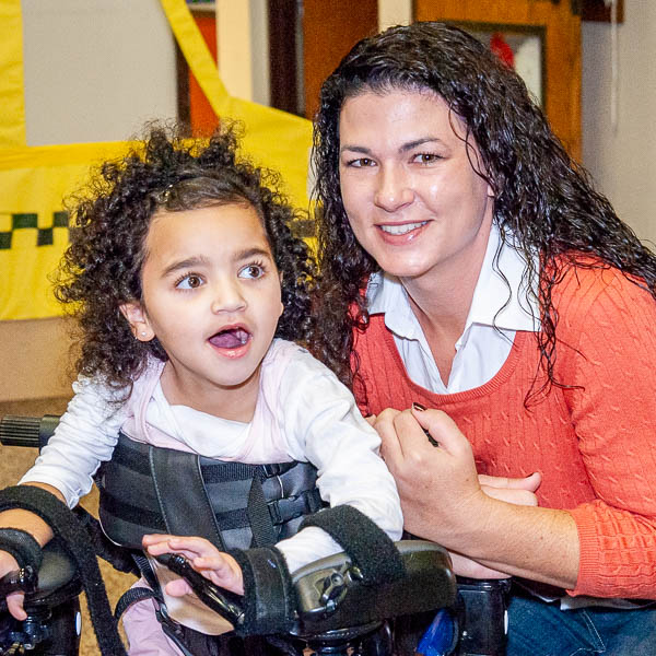 Educator posing with student using assistive device