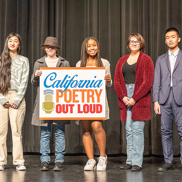 Competitors posing on stage holding a CA Poetry Out Loud sign