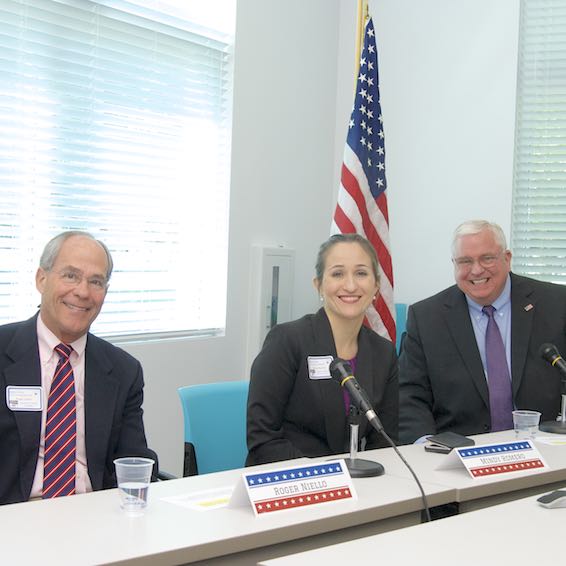 Roger Niello, Mindy Romero, and David Gordon seated in front of mics