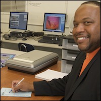 Daniel Watts posing at desk in classroom