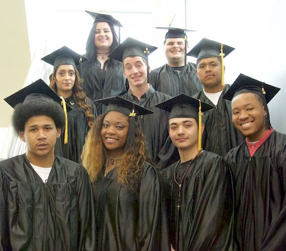 Group of graduates poses in caps and gowns