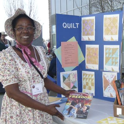 Volunteer standing in front of quilting display