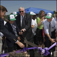 Dignitaries cutting purple ribbon with ceremonial scissors