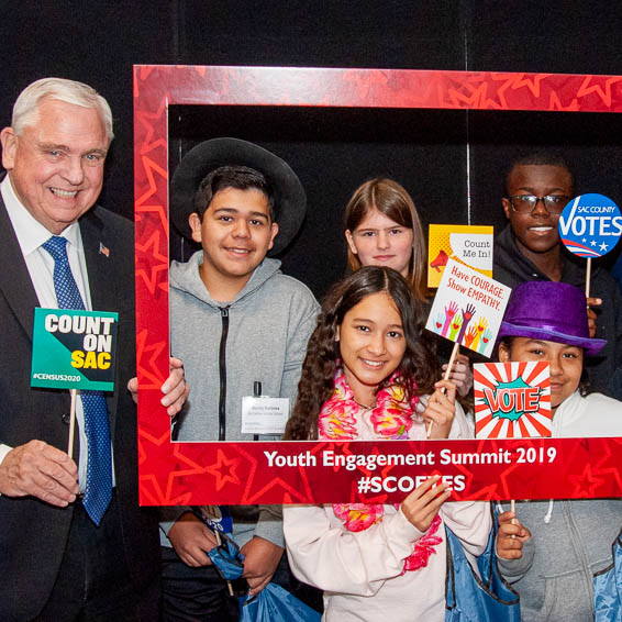 Students posing with superintendent and holding engagement summit photo frame