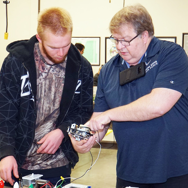 Teacher and student discussing at electrical wiring