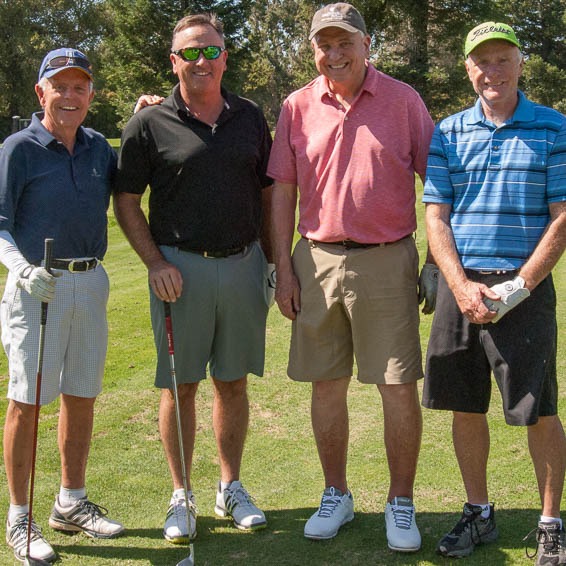 Group of four golfers holding clubs