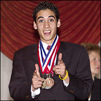 Smiling student poses with multiple medals around his neck