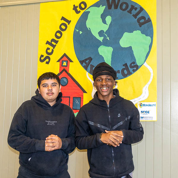 Students in front of School to World sign