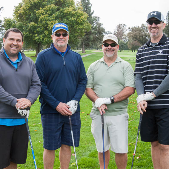 Group of four golfers leaning on their clubs