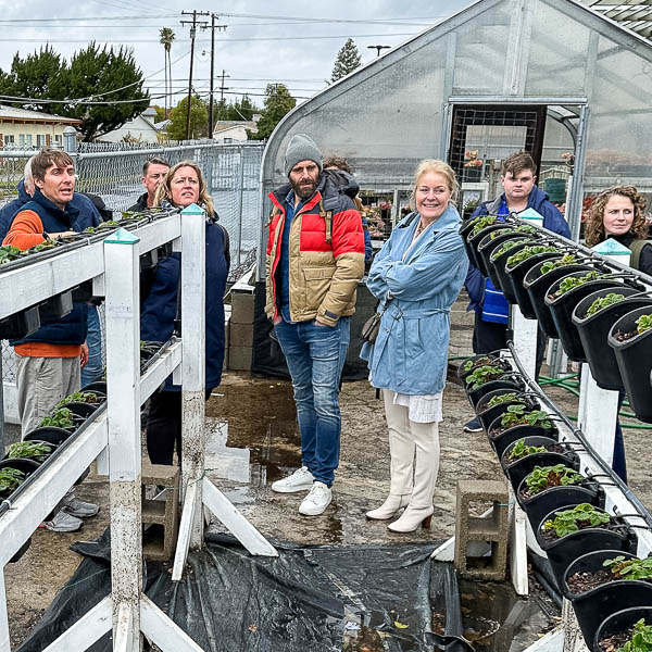 Visitors outside a greenhouse, talking to teacher