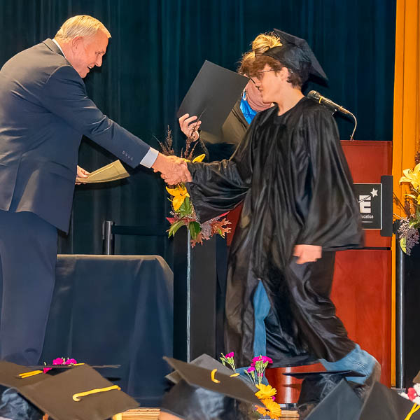 Dave Gordon shaking hands with a graduate
