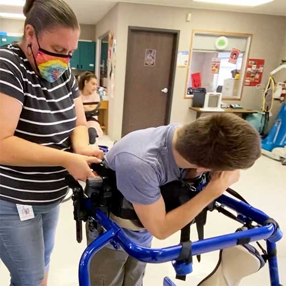 Alstrum helping student strap into assistive device