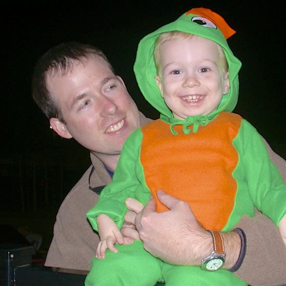 Smiling father holding son in pumpkin costume