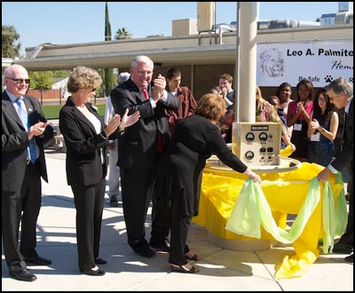 Board members pull ribbon and wrapping off base of solar panels