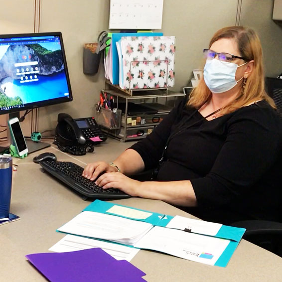 Staff member wearing mask preparing to type on computer keyboard