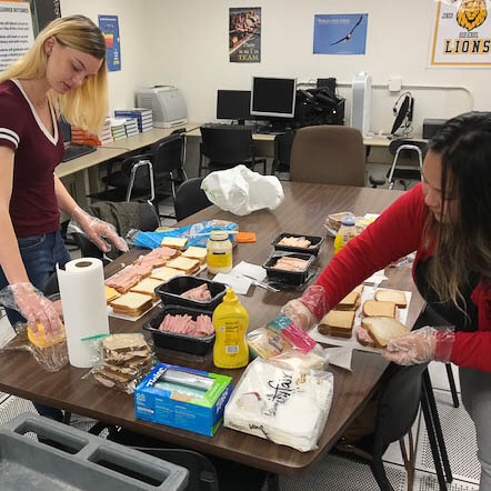 Heather Oswalt and another student prepare sandwiches in a classroom
