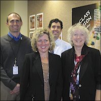 Employee artists posing in front of event poster