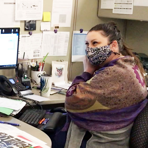 Staff member adjusting mask while sitting at desk