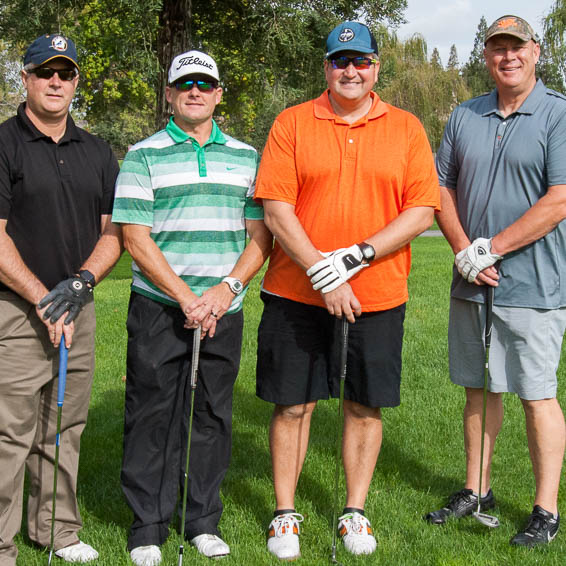 Group of four golfers holding clubs