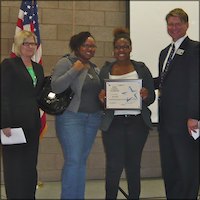 Erin Newby on stage holding certificate