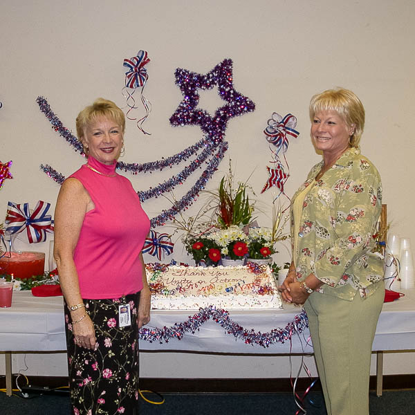 Staff posing in front of decorated table with cake and punch