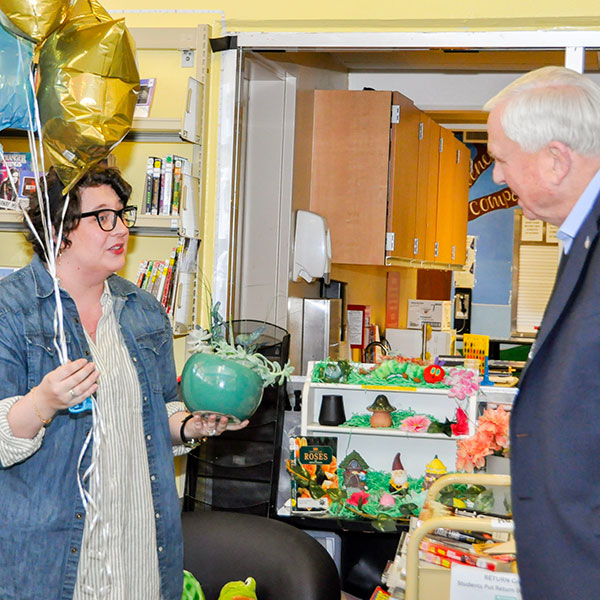 Jessie Storrs receiving balloons and a plant arrangement from Superintendent Gordon