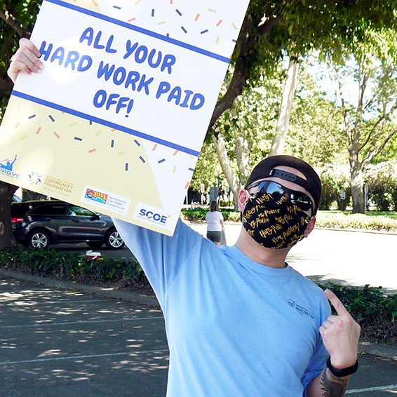 Staff member waving sign: All Your Hard Work Paid Off!