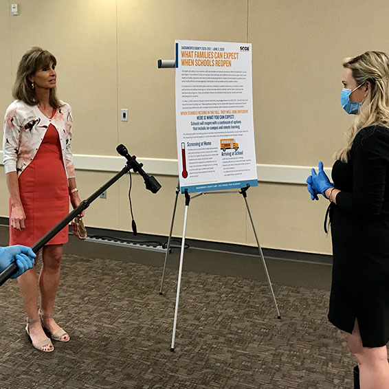 Superintendent being interviewed by a reporter who is wearing mask and gloves