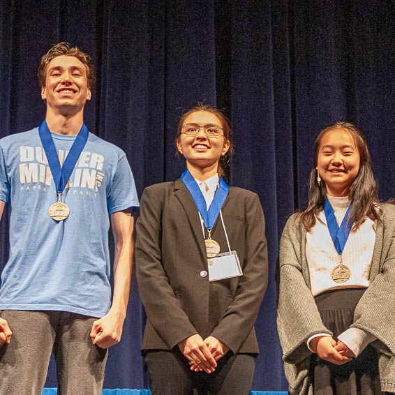 Students on stage receiving medals