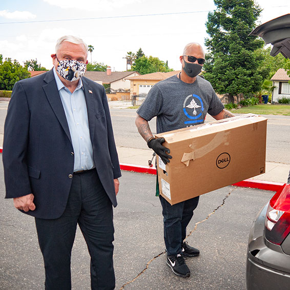 Dave Gordon with Eric Nicholls loading a cardboard computer box into a car trunk.