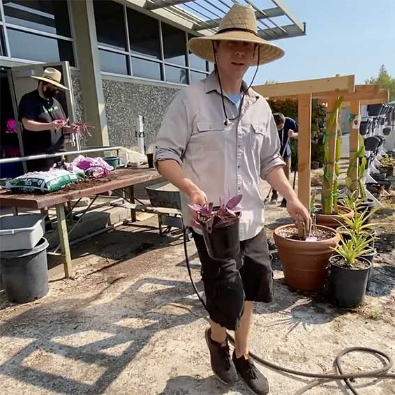 Teacher carrying potted plant in outdoor classroom garden