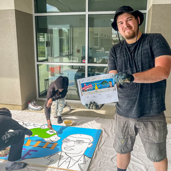 Artist holding plan for mural as it's being painted