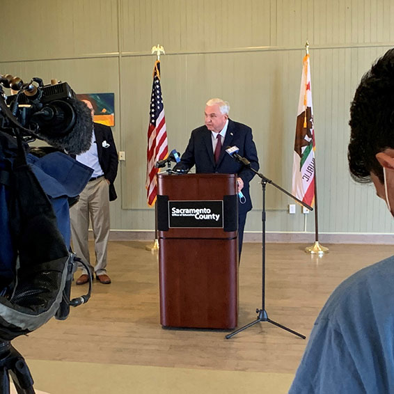 Dave Gordon speaking in front of news camera at press conference