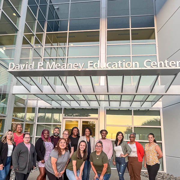 Group of adults posing in front of SCOE building