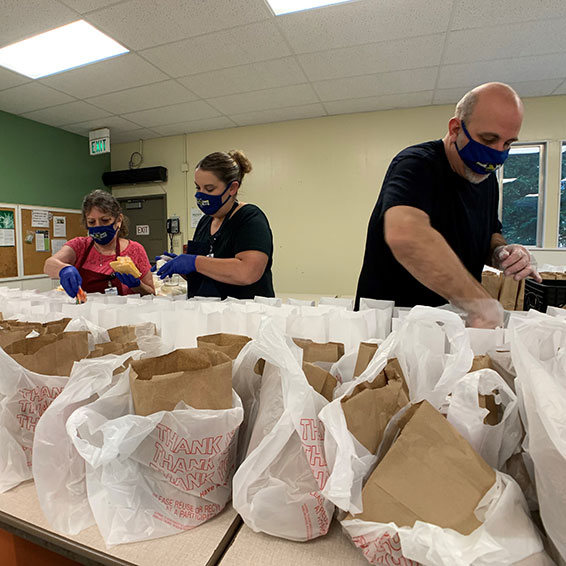 Sly Park kitchen staff, wearing masks, prepare bagged student meals