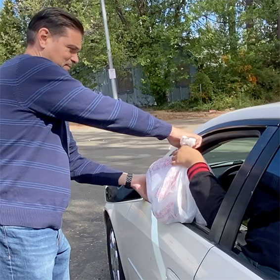 Staff member handing bag of food through car window