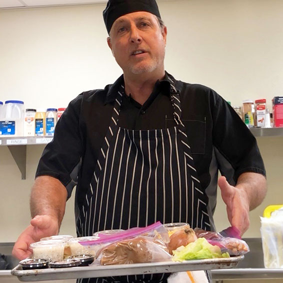 Chef holding baking tray stacked with ingredients