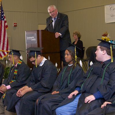 Dave Gordon speaking to seated graduates.