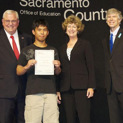 Dave Gordon, Jacquelyn Levy, and Greg Geeting present a certificate to a student.