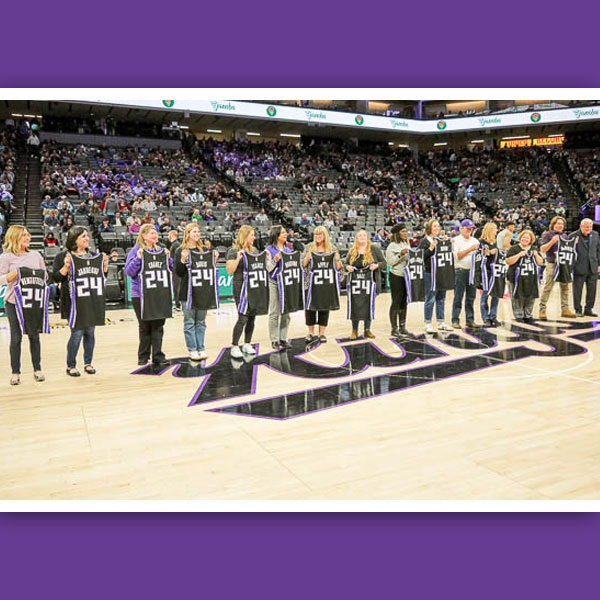 District Teachers of the Year 2024 lined up on center court holding custom jerseys
