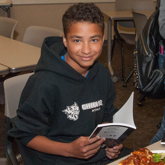 Seated student holding up book