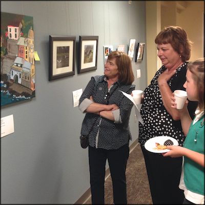 Visitors enjoying snacks while looking at hanging employee artwork