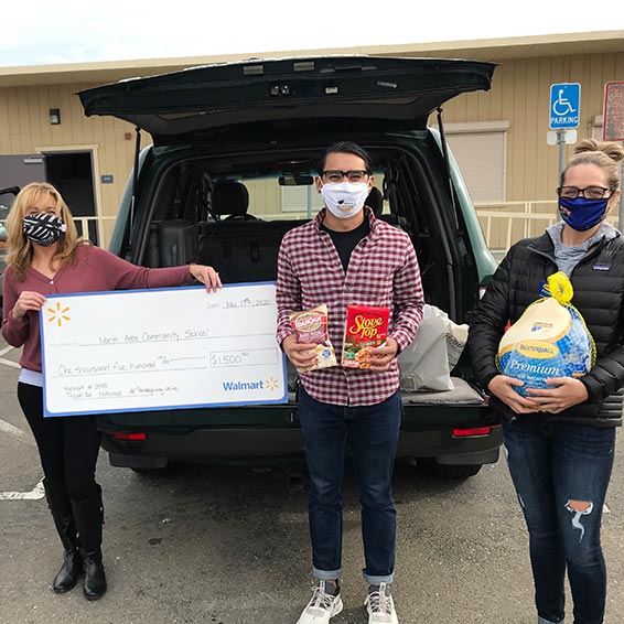 Staff member holding large, $1,500 Walmart check