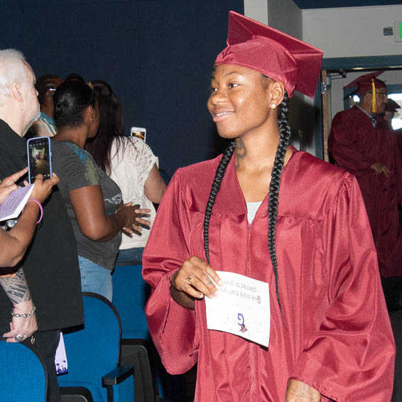 Graduate in cap and gown walking down aisle