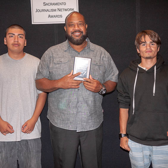 Students posing with teacher holding plaque