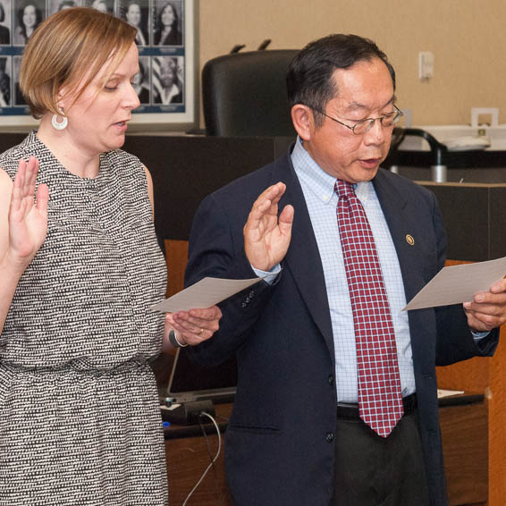 Joanne Ahola and Harold Fong with hands raised, being sworn in