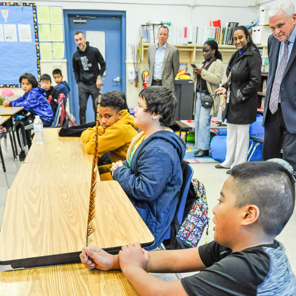 Visitors and students listening to a student holding a feather