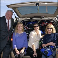 Staff sitting behind minivan full of backpacks