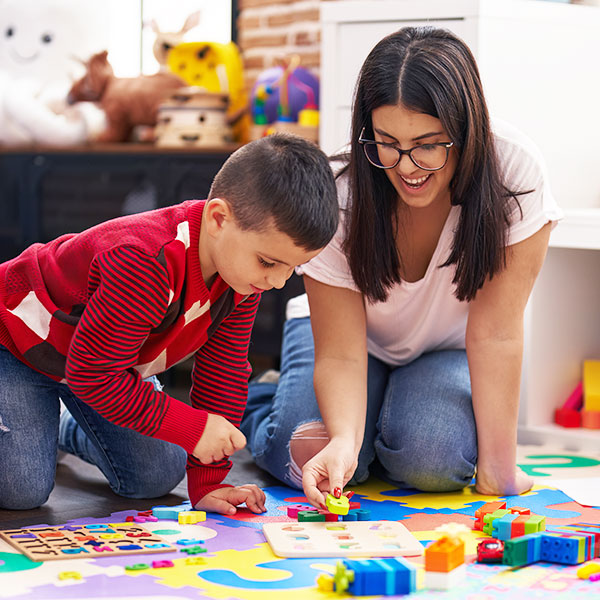 Preschool teacher teaching numbers to child using a puzzle