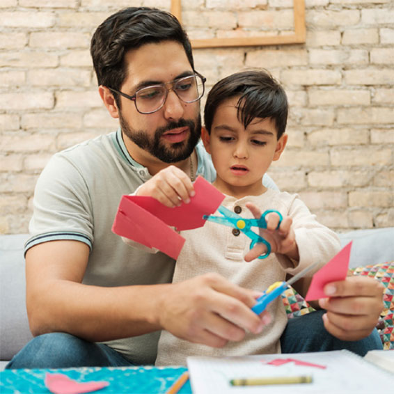 Father helping child cut shapes with scissors